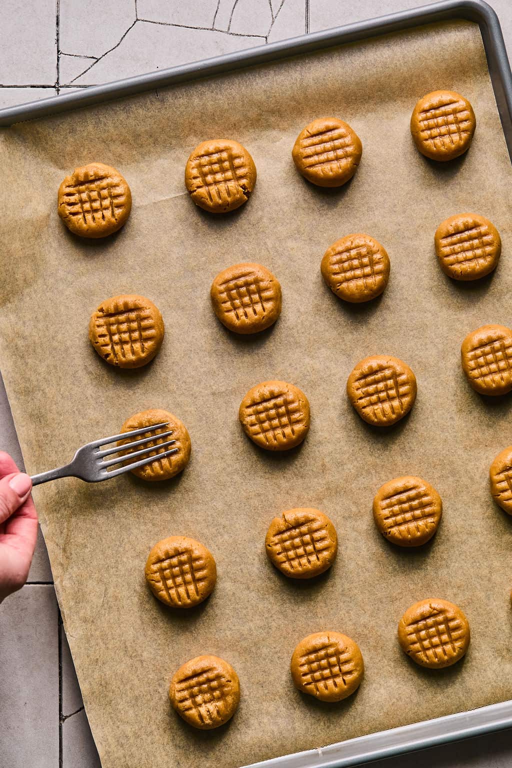 pressing a criss cross pattern into peanut butter cookie dough with a fork.