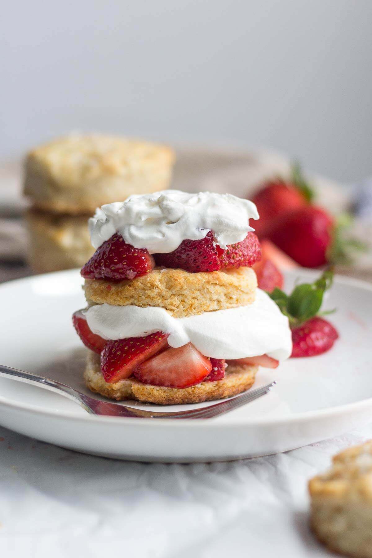 a fork resting next to a pieces of Healthy strawberry shortcake on a white plate