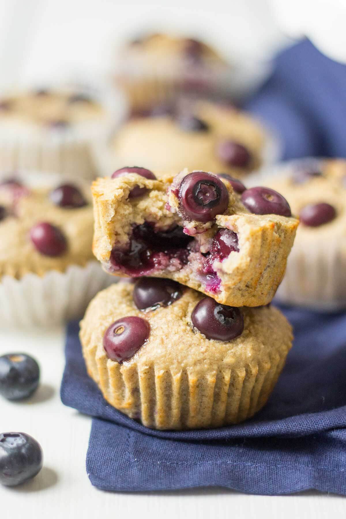 triple berry blender muffins stacked on top of each other and a bite taken out of the top one