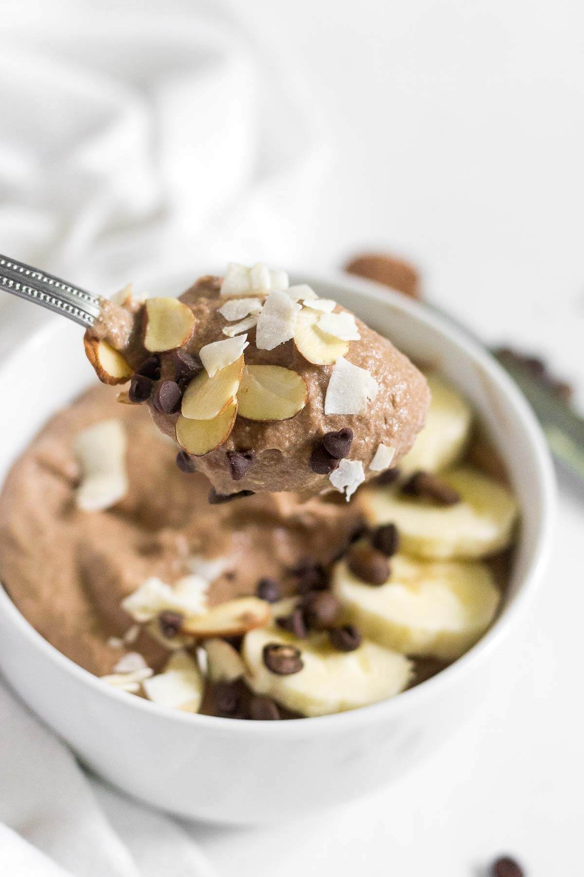 spoonful of mocha protein smoothie bowl with almond slivers and coconut flakes