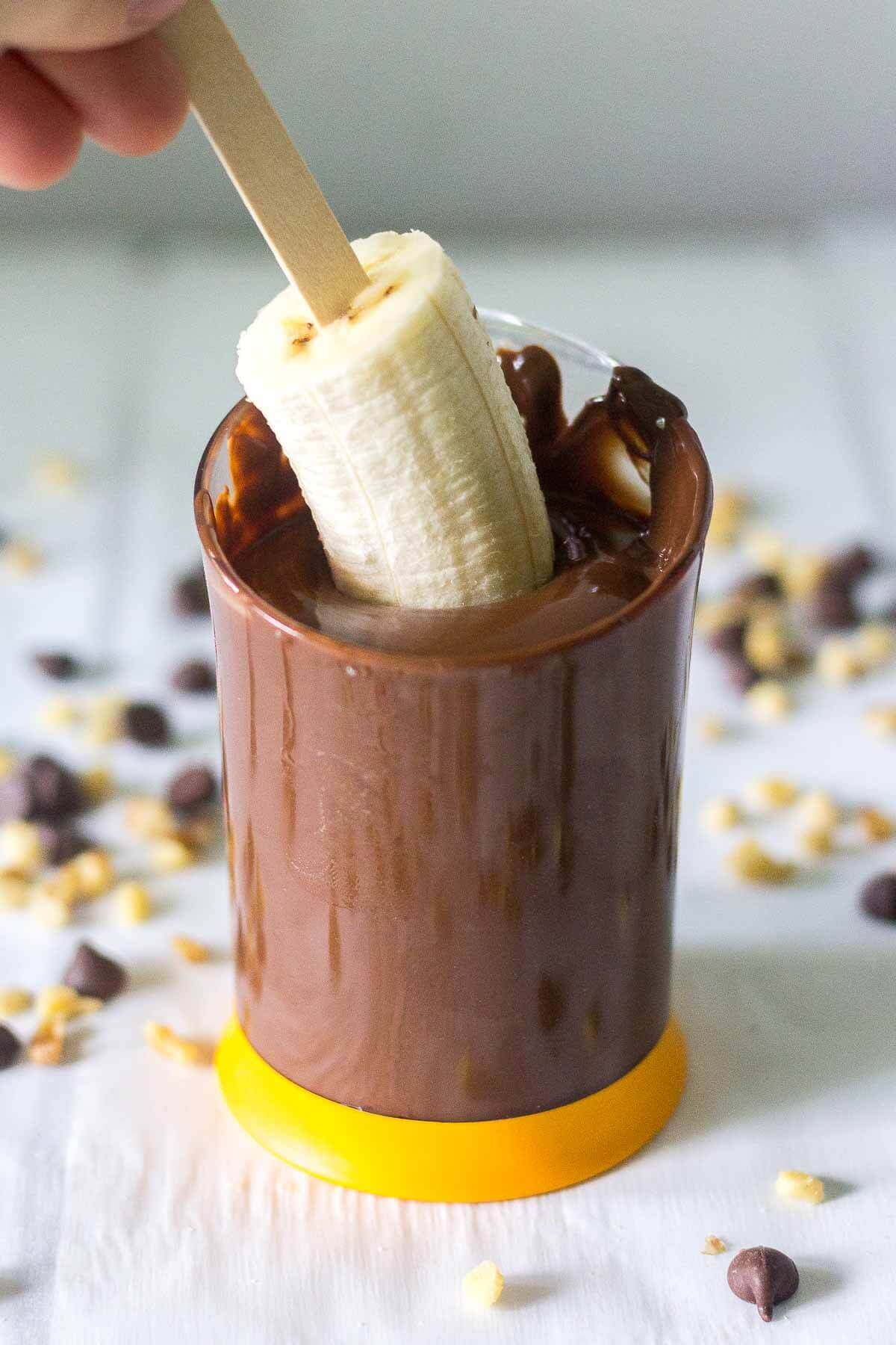 paleo frozen bananas getting dipped into melted chocolate