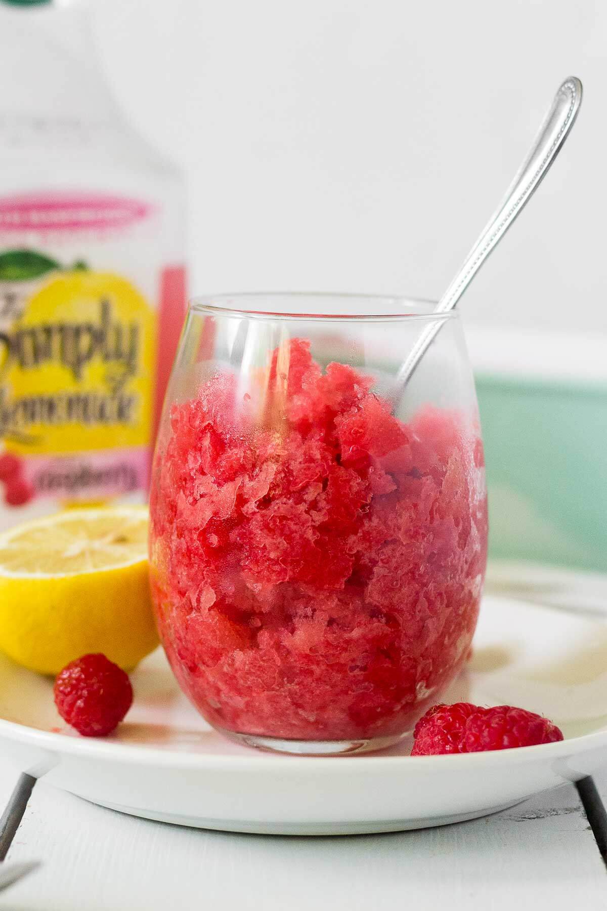 glass of raspberry lemonade granita with a spoon dipped into it