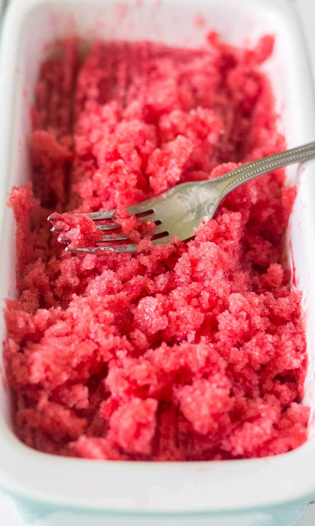 fork dipped into a container of raspberry lemonade granita