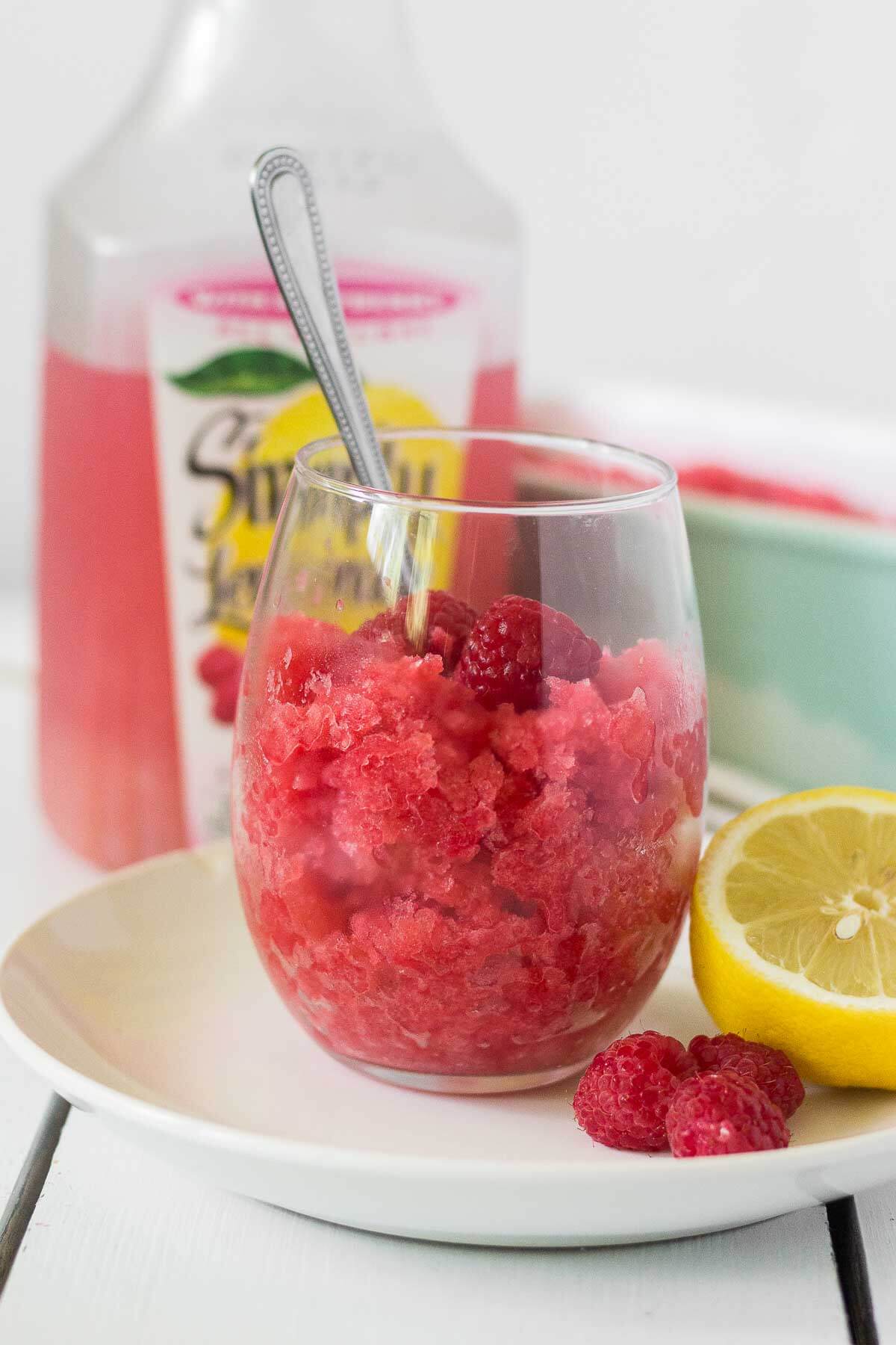 up close of a glass of raspberry lemonade granita with a spoon dunked into it