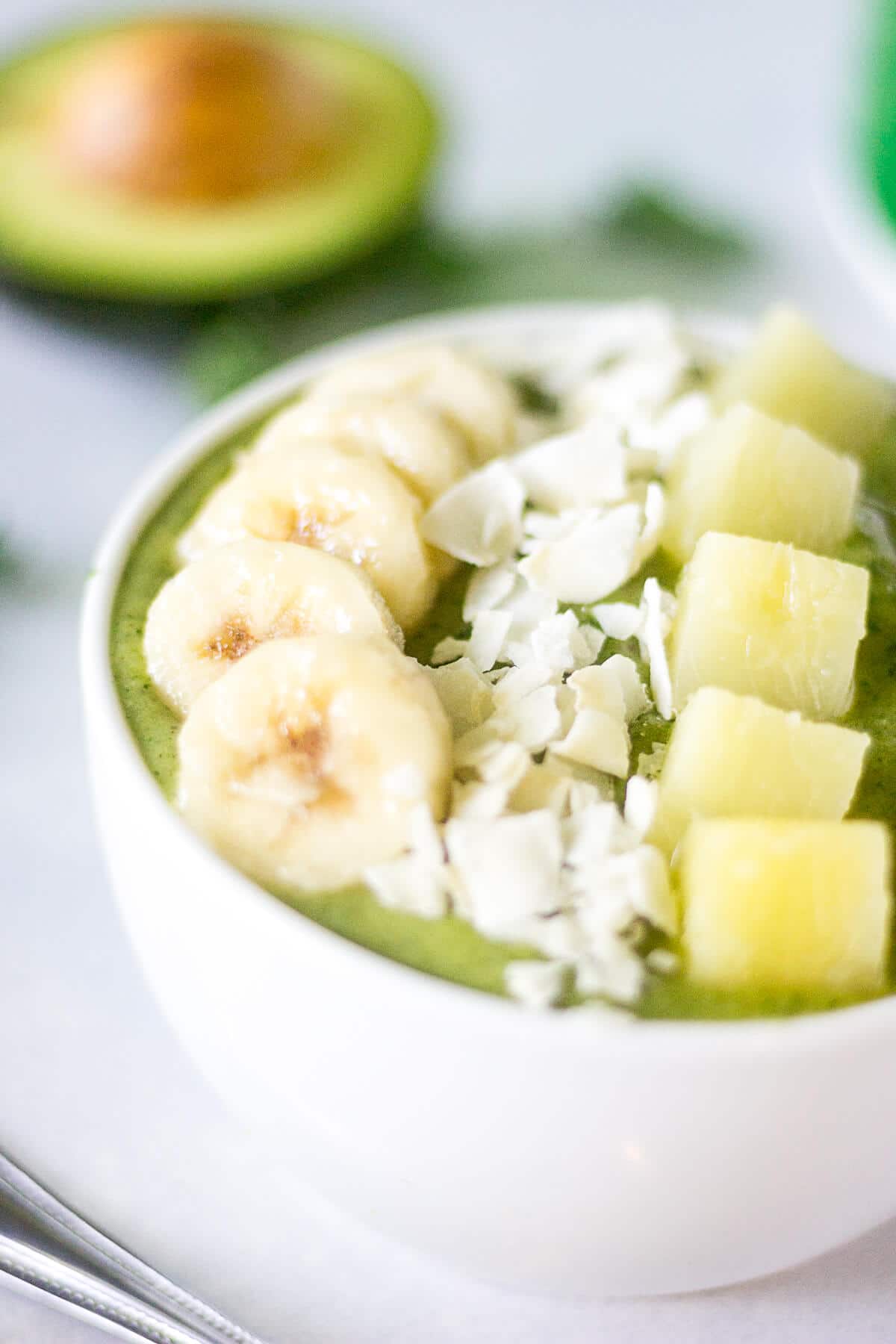 close up of a green smoothie bowl on a counter next to a resting spoon