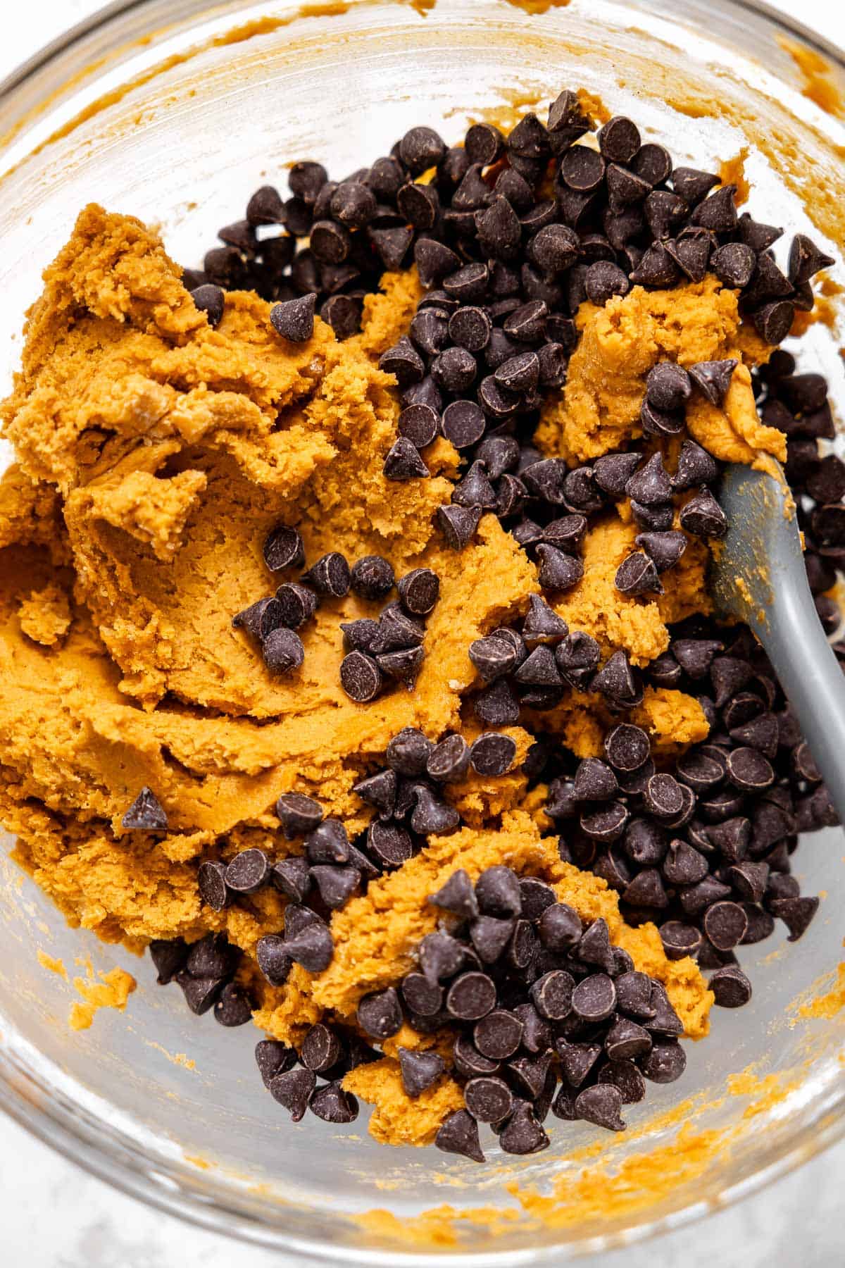 chocolate chips on top of pumpkin pudding cookie dough in a mixing bowl.