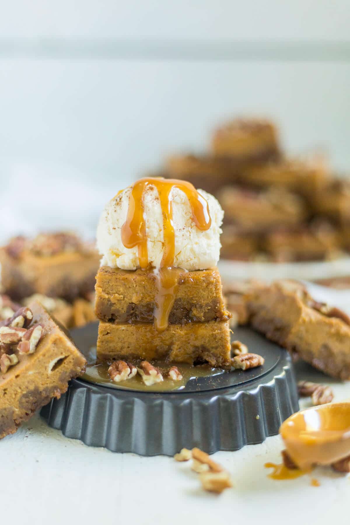 Pumpkin pie bars are a fun twist on a classic Thanksgiving recipe! The crust is made from crushed gingerbread and the bars are just like pumpkin pie and topped with pecans, caramel, ice cream and more!