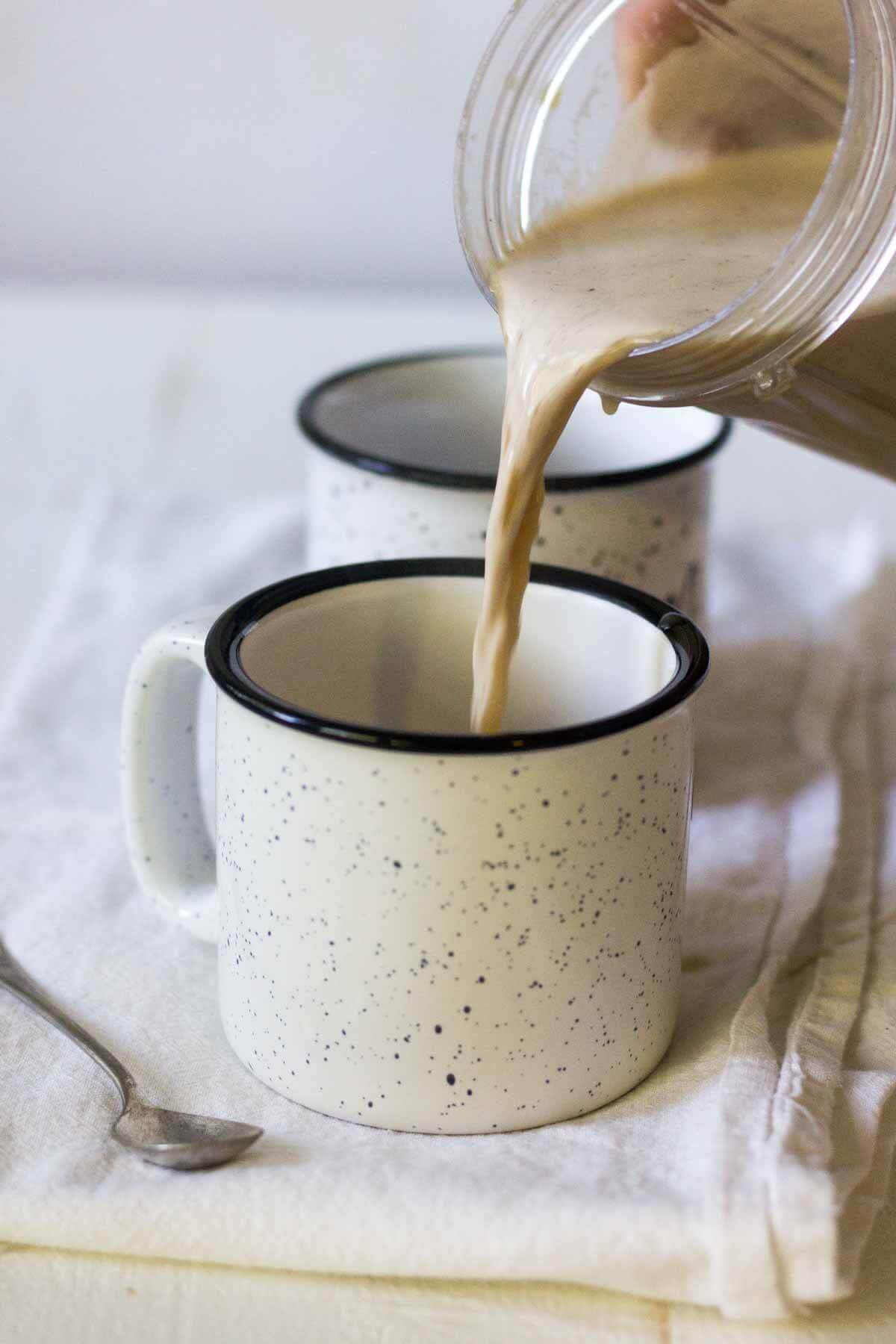 Bulletproof coffee getting poured into a mug resting on a white dish towel