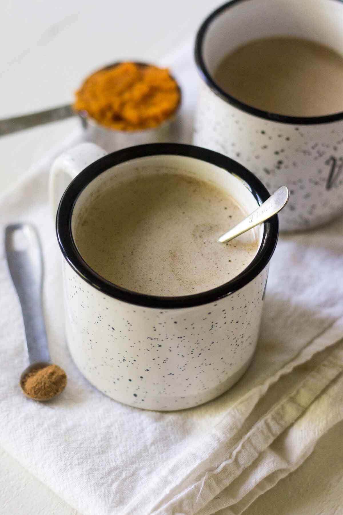 Bulletproof coffee in a mug on the counter with a tiny metal spoon