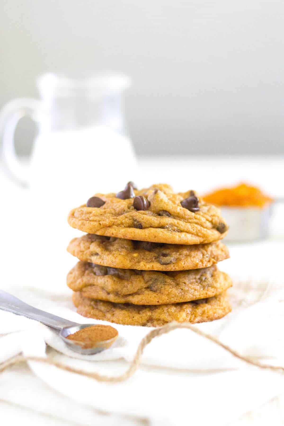 pumpkin chocolate chip cookies on a towel with a glass of milk