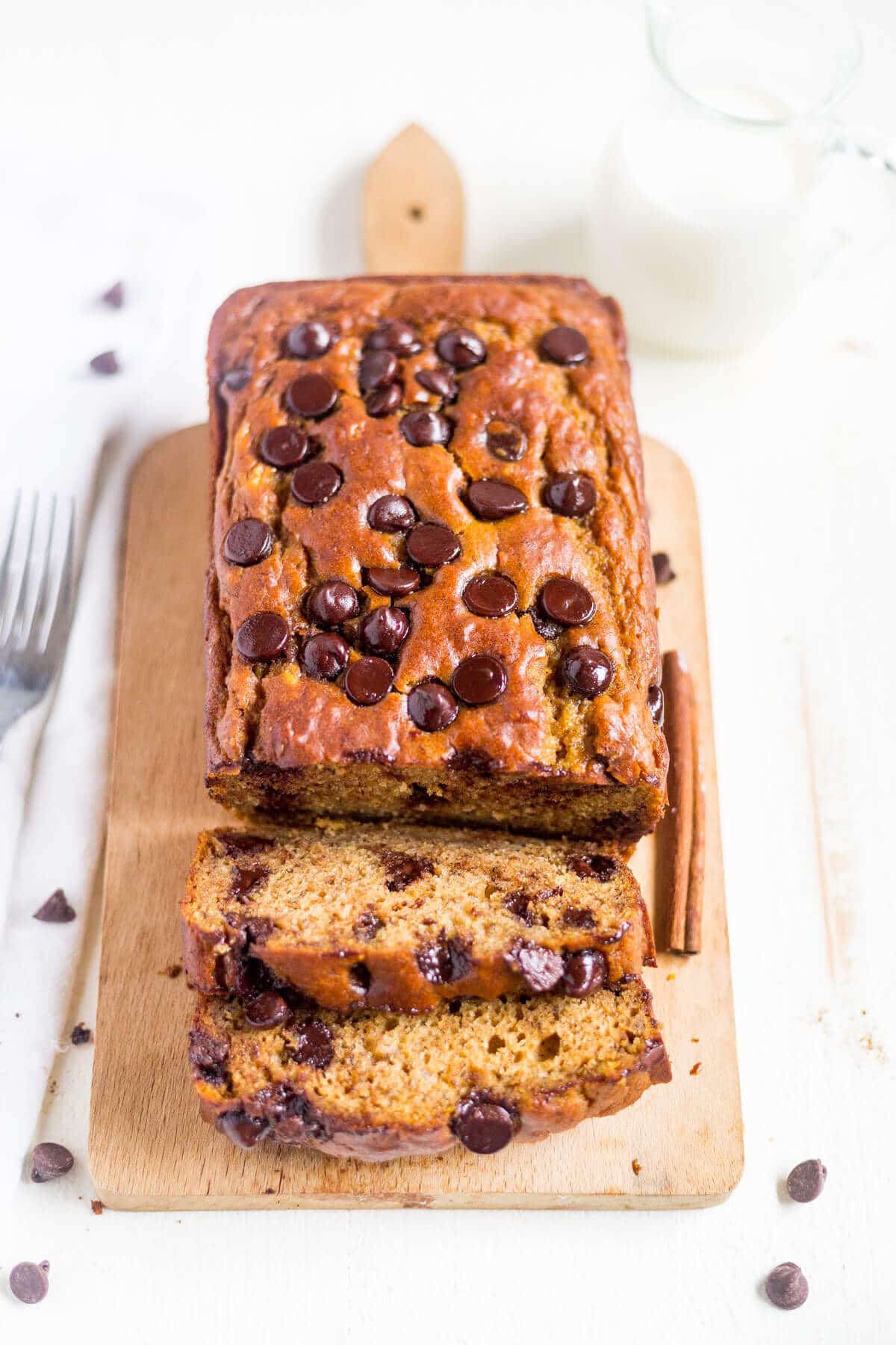 loaf of healthy pumpkin banana bread on a cutting board with first couple of pieces sliced