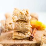 Stack of three snickerdoodle apple pie bars next to cinnamon sticks