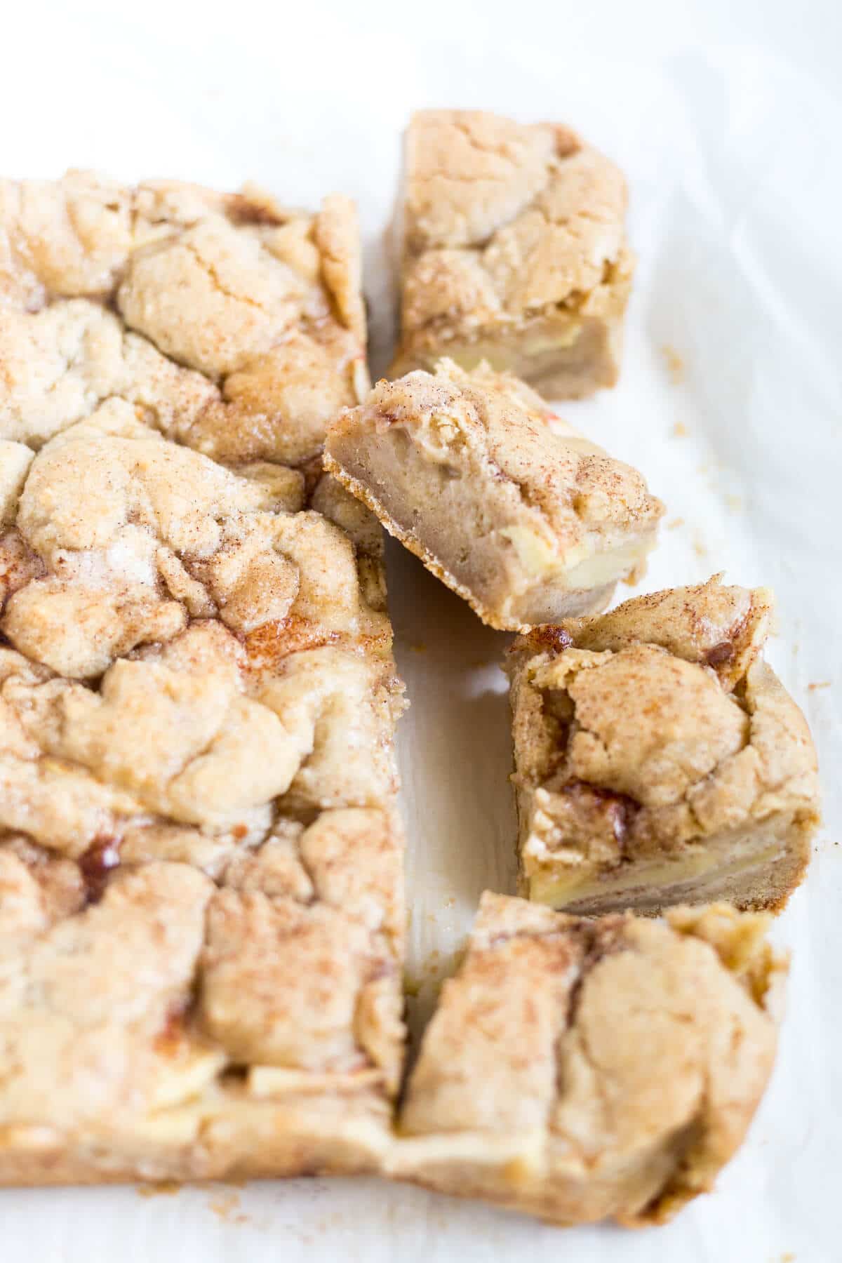 Sweet and gooey snickerdoodle apple pie bars with the first row cut up in squares