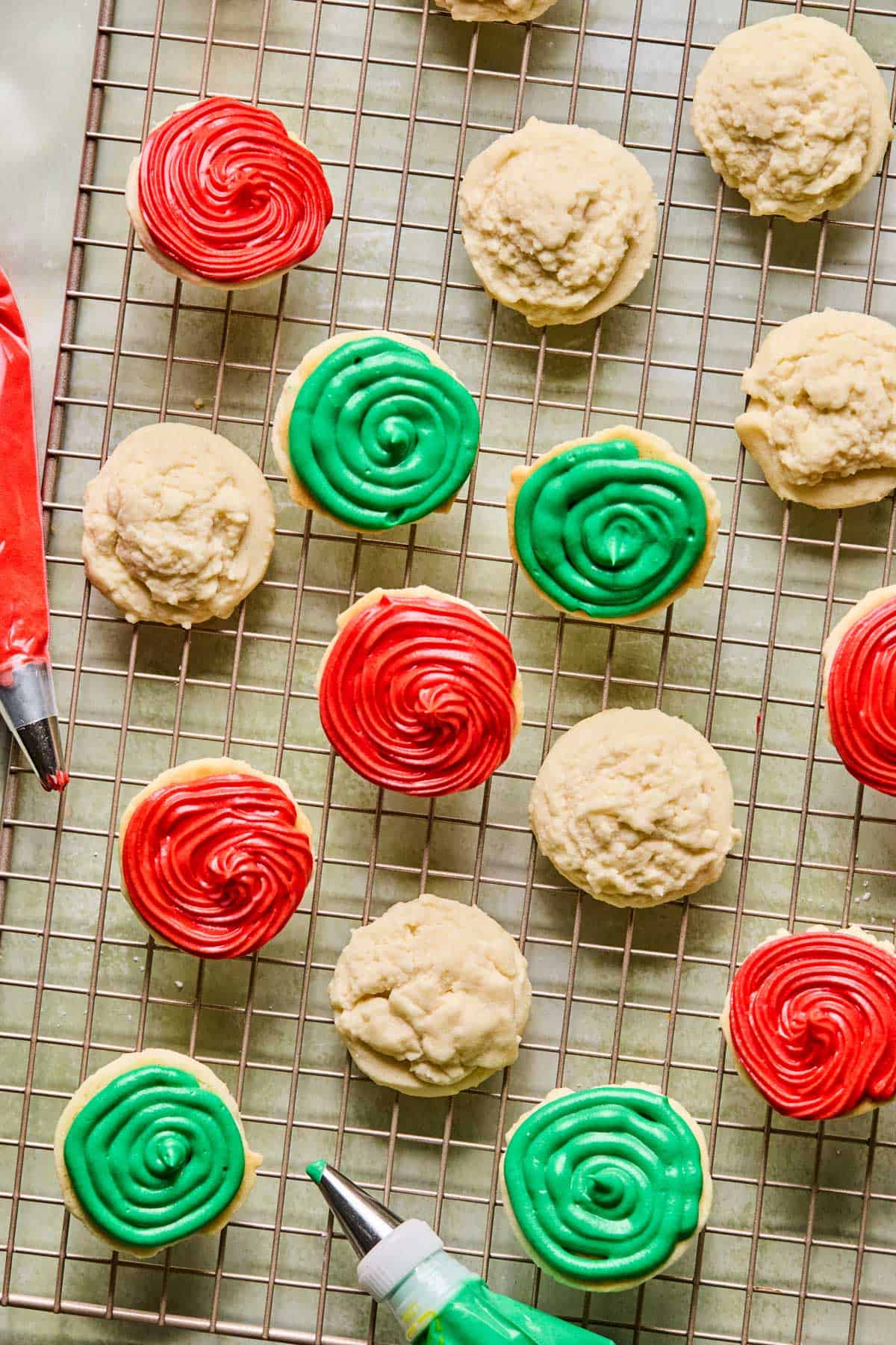 piping cream cheese frosting onto sandwich cookies cooling on a wire rack.