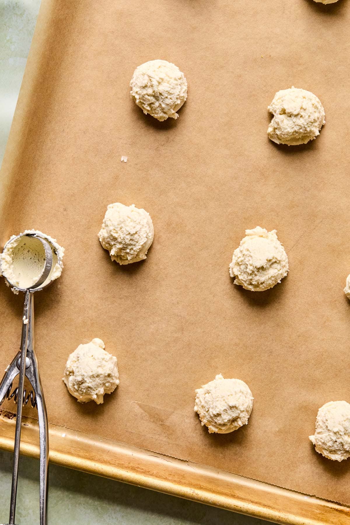 melting moments cookie dough dropped on a parchment lined baking sheet.