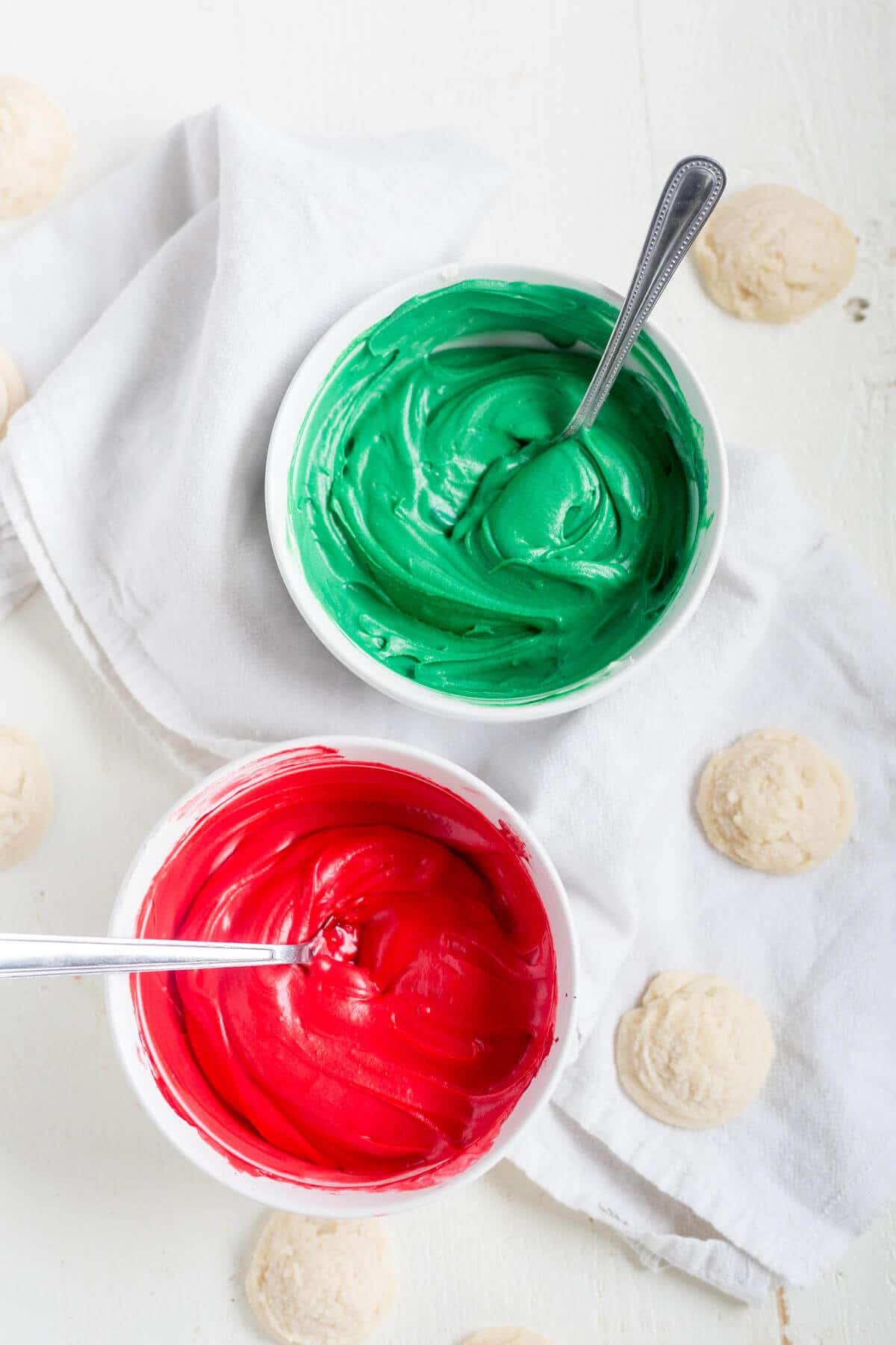 spoons in two bowls of icing, one red and one green