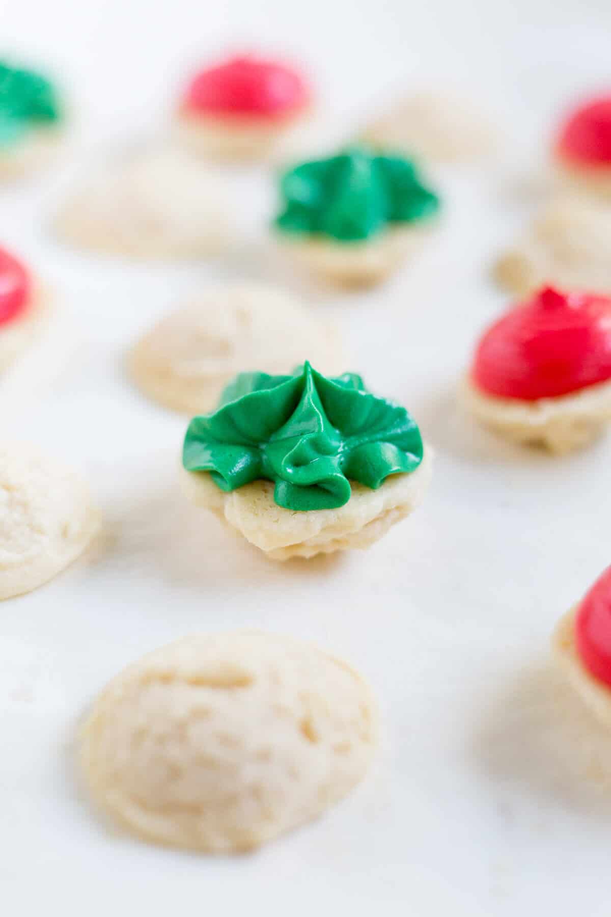 Melting moments sandwich cookies lying open faced with green icing