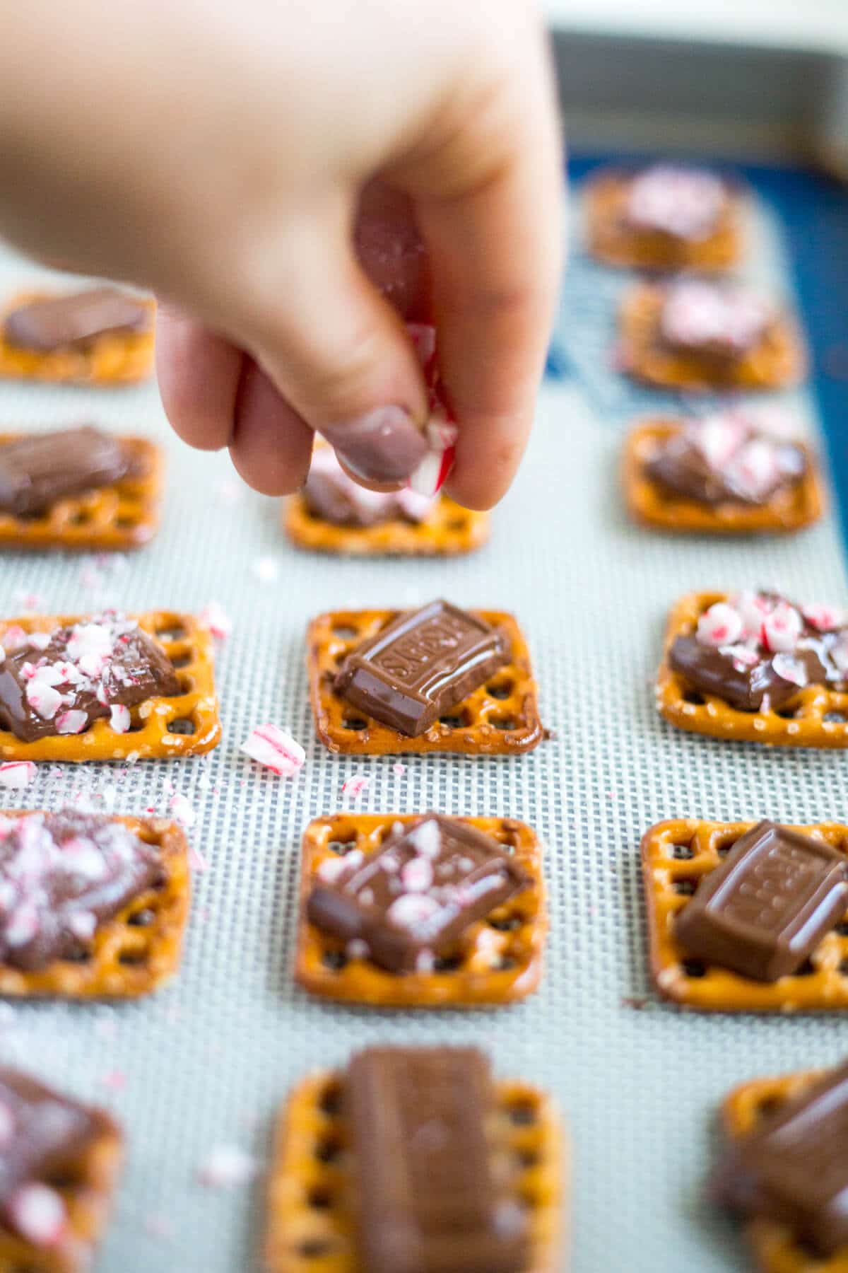 This peppermint pretzel bite recipe will be a huge hit! A pretzel, topped with milk chocolate and sprinkled with peppermint pieces, you can make these bite-sized holiday desserts in under 10 minutes!