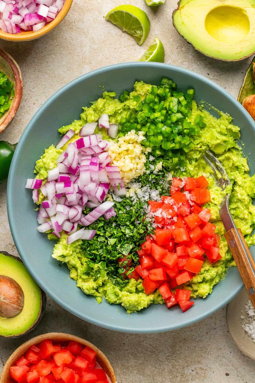 mashed avocado in a bowl topped with guacamole ingredients