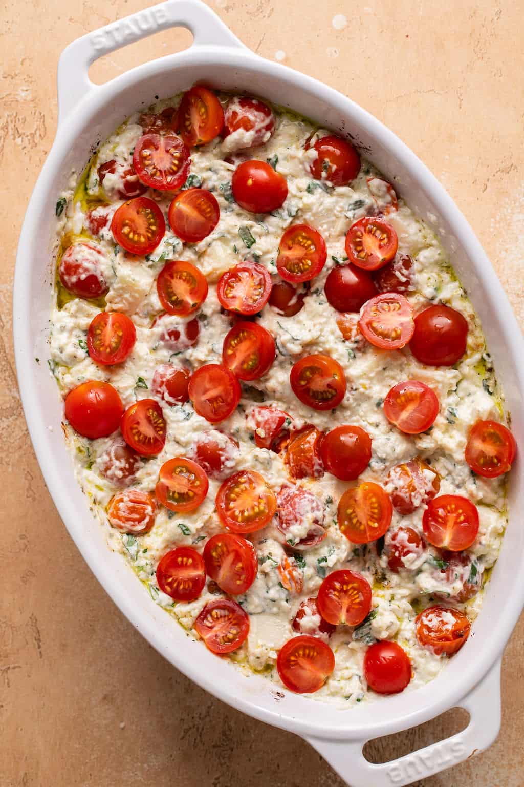 unbaked caprese dip in a baking dish topped with tomatoes