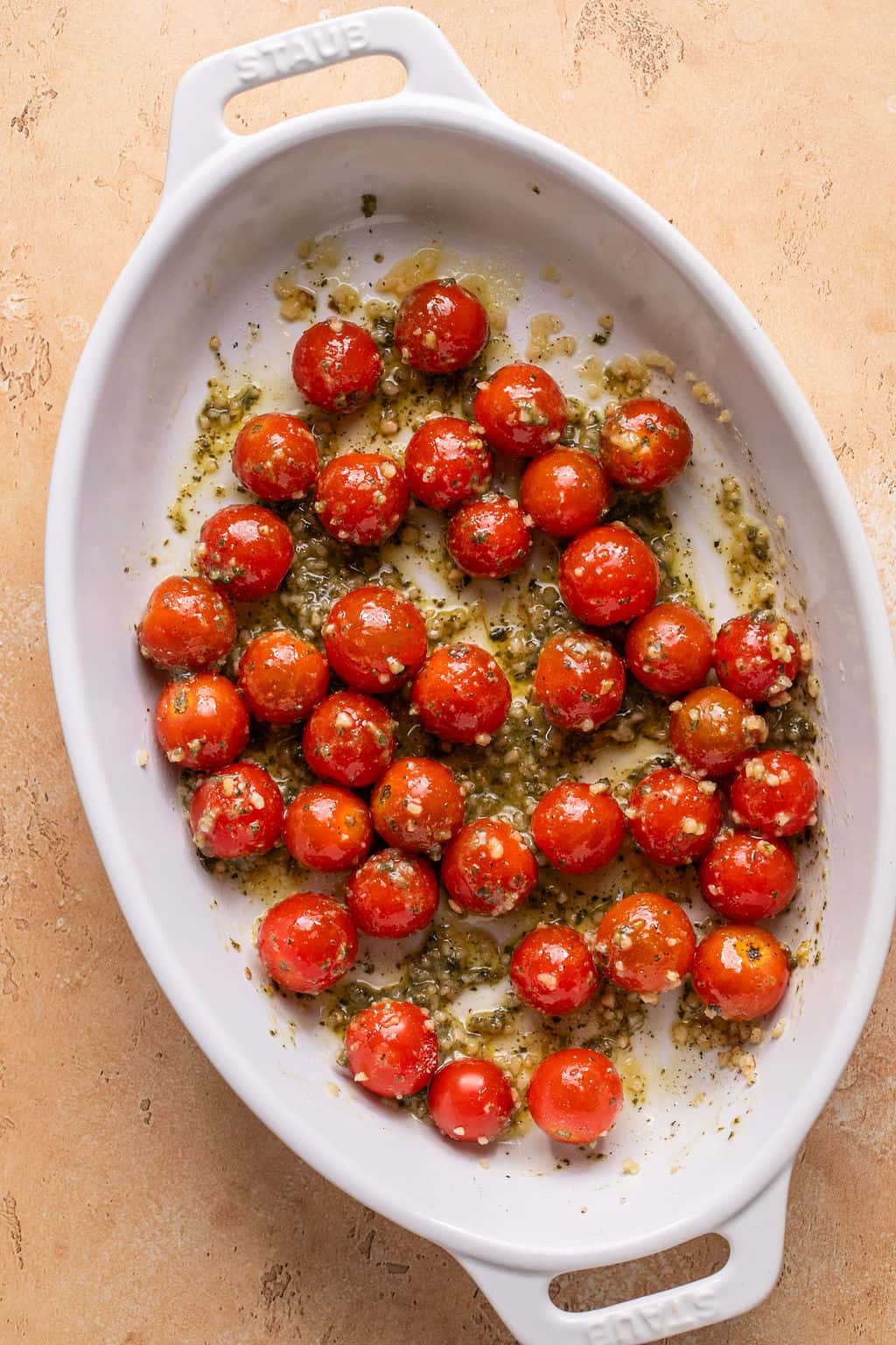 cherry tomatoes in a baking dish with pesto and garlic