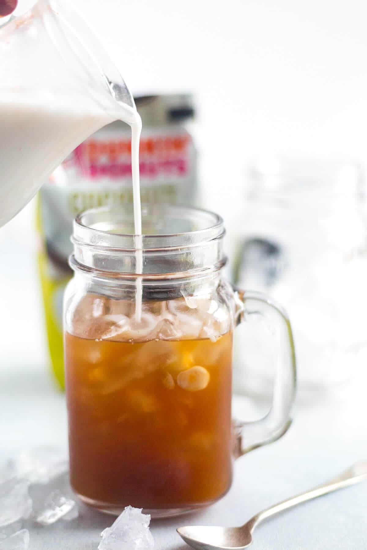 coconut milk being poured into a mocha coconut iced coffee