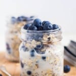 Easy, quick, and filling gluten-free, dairy-free blueberry overnight oats in a mason jar on a counter with blueberries covering the top of the jar
