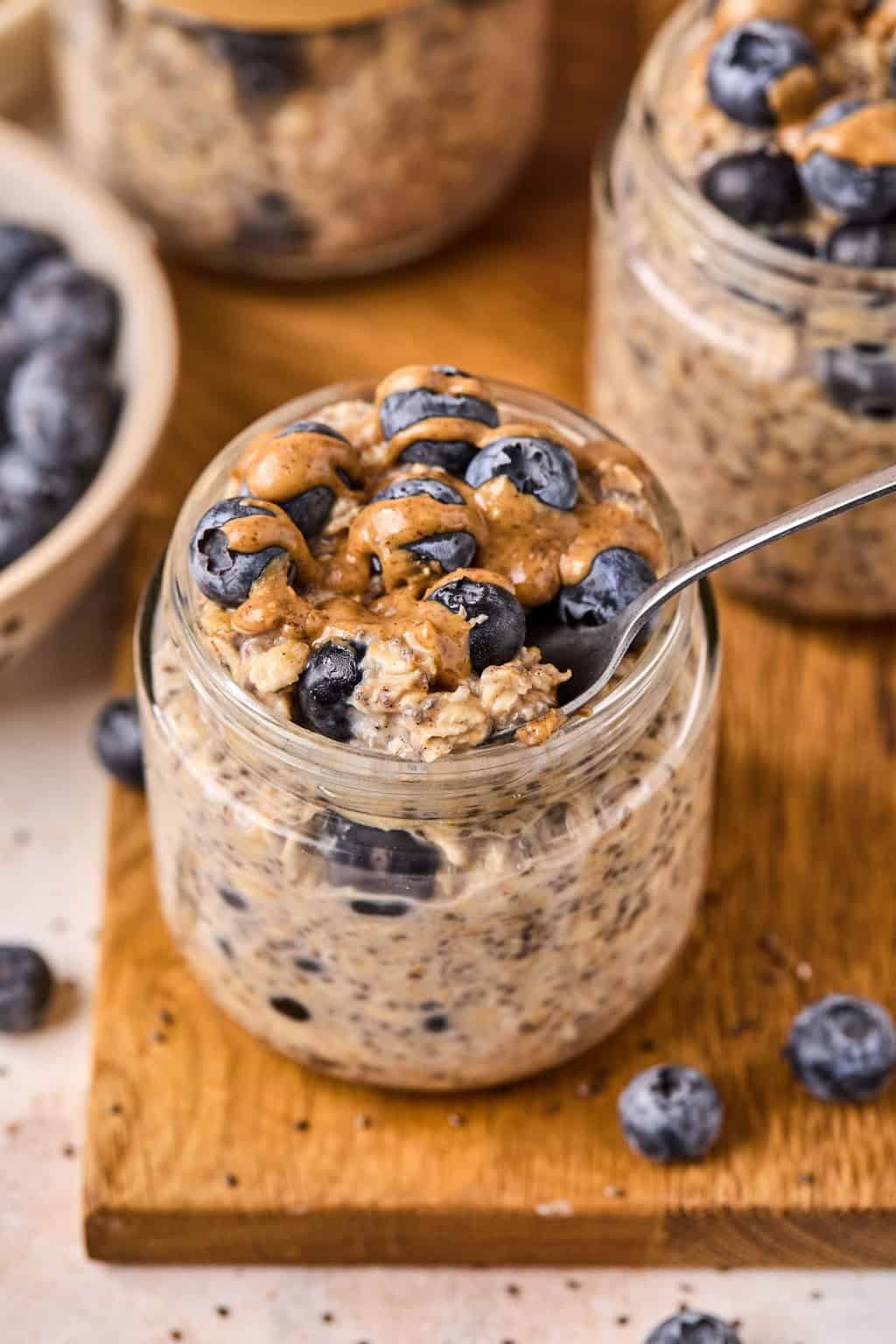 blueberry overnight oats in a jar topped with fresh blueberries and almond butter.