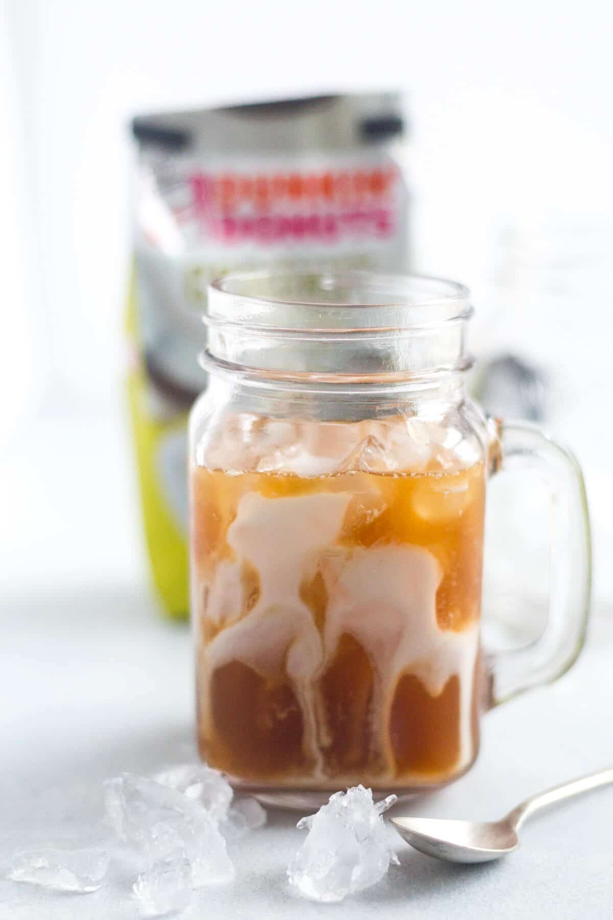 coconut iced coffee in a glass mug with coconut milk running down the sides