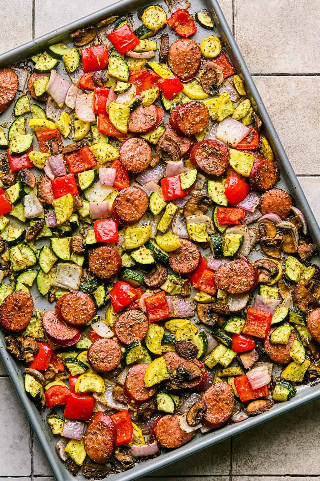 sheet pan sausage and veggies cooling on a counter.