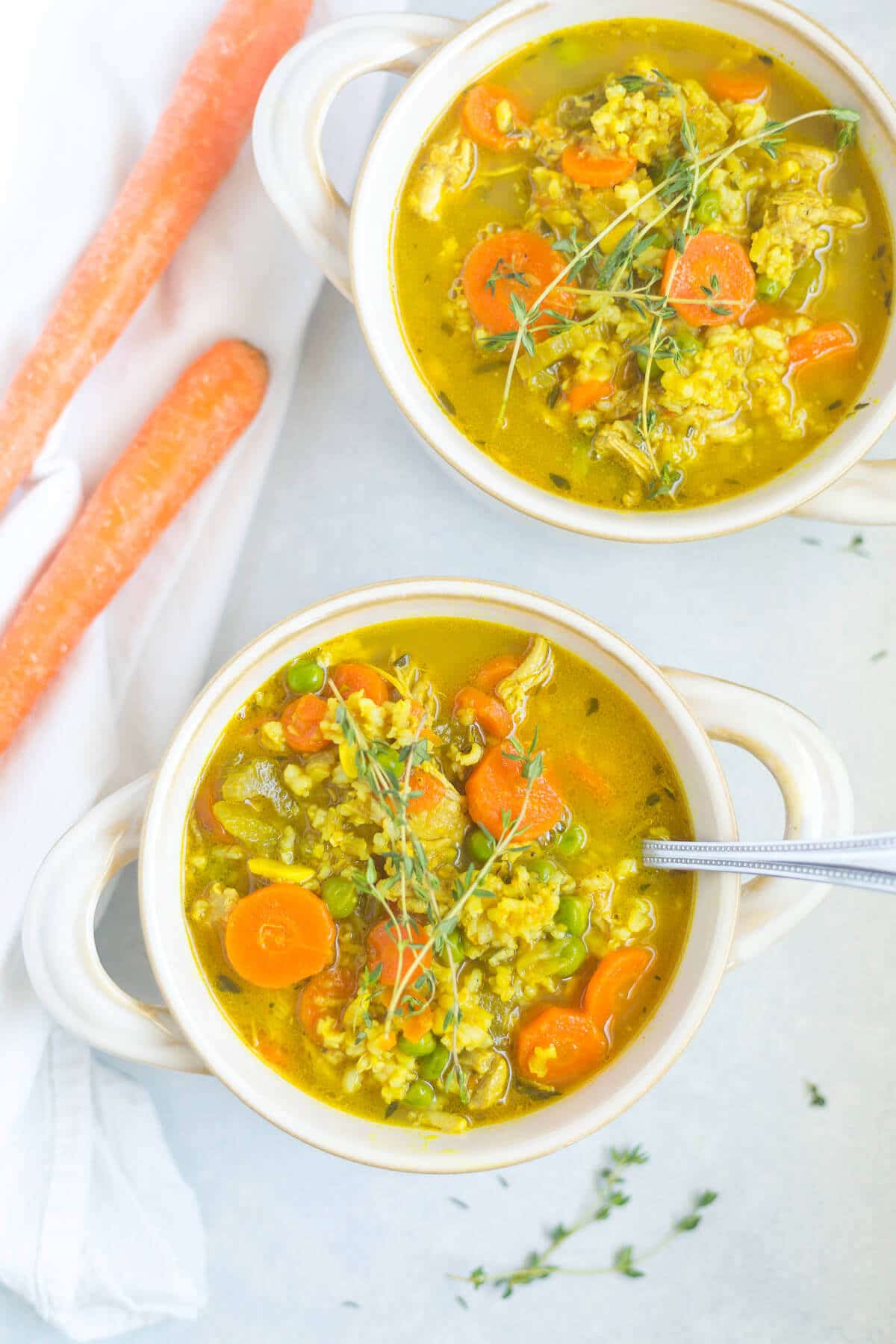 two bowls of low calorie chicken soup with fresh herbs on top