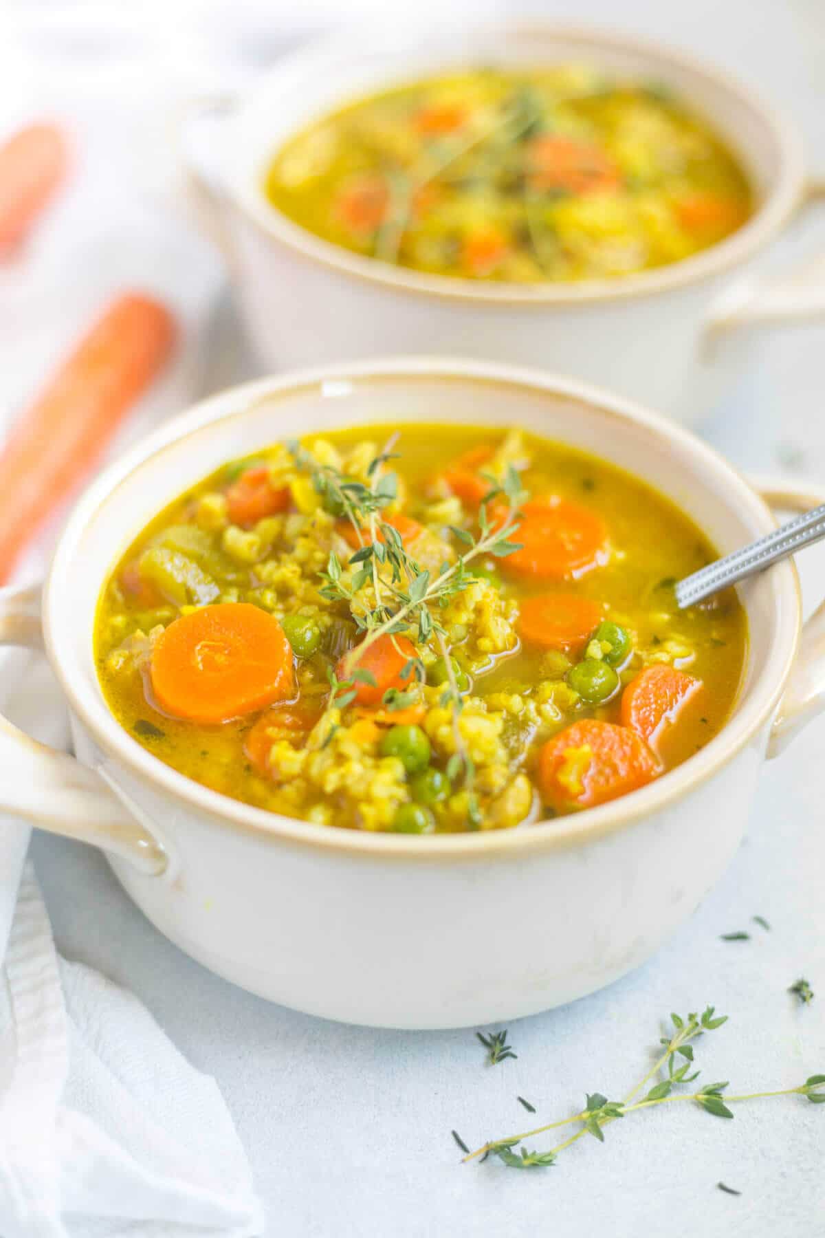 healthy chicken soup in a white soup bowl topped with fresh thyme