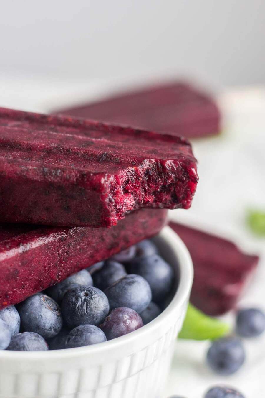 blueberry popsicles stacked on top of each other with a bite taken out of one