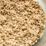 Cooked brown rice in a clear glass bowl, ready to be added to PCOS-friendly chicken soup.