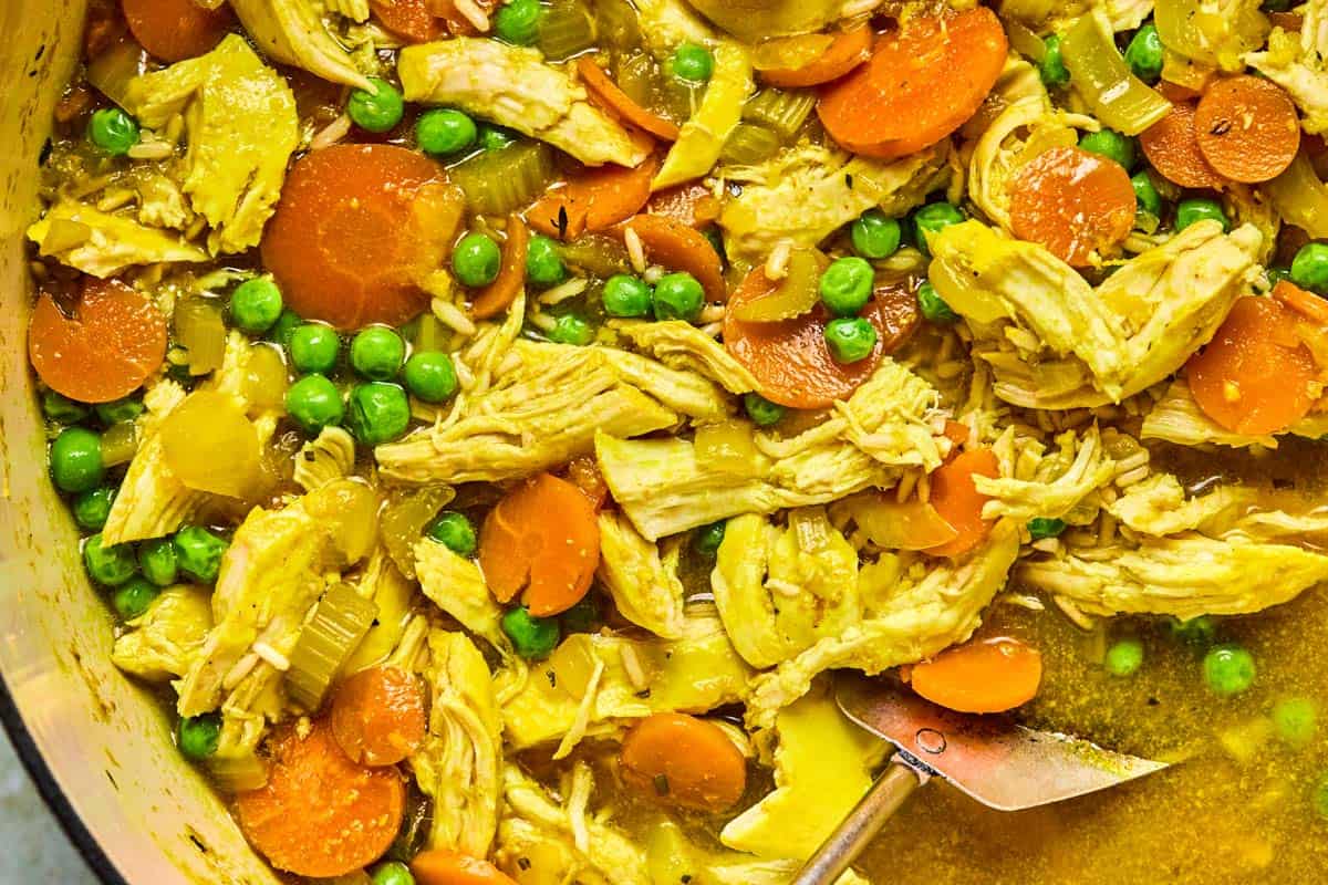 PCOS-friendly chicken soup in a Dutch oven with carrots, peas, shredded chicken, and brown rice.