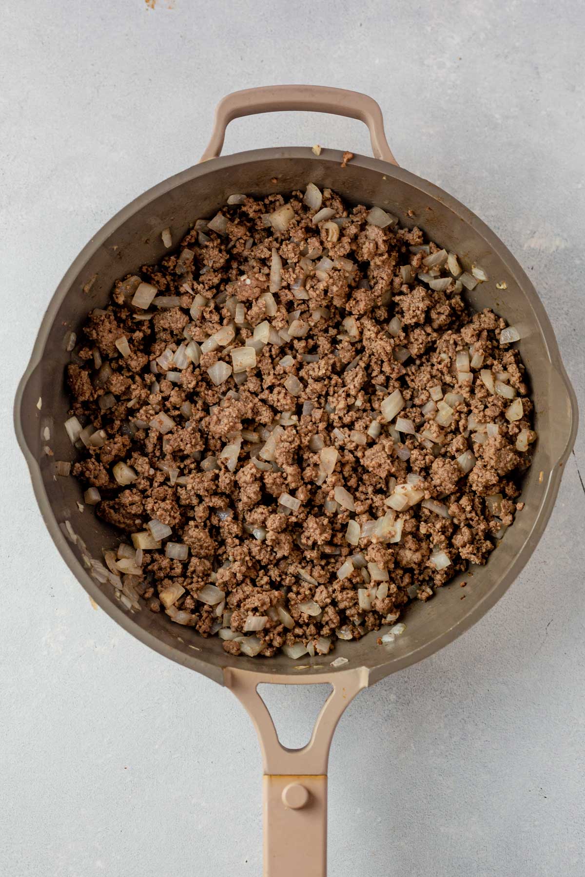 cooked ground beef and onion in a skillet