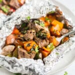 steak potato foil packets on a plate with a fork