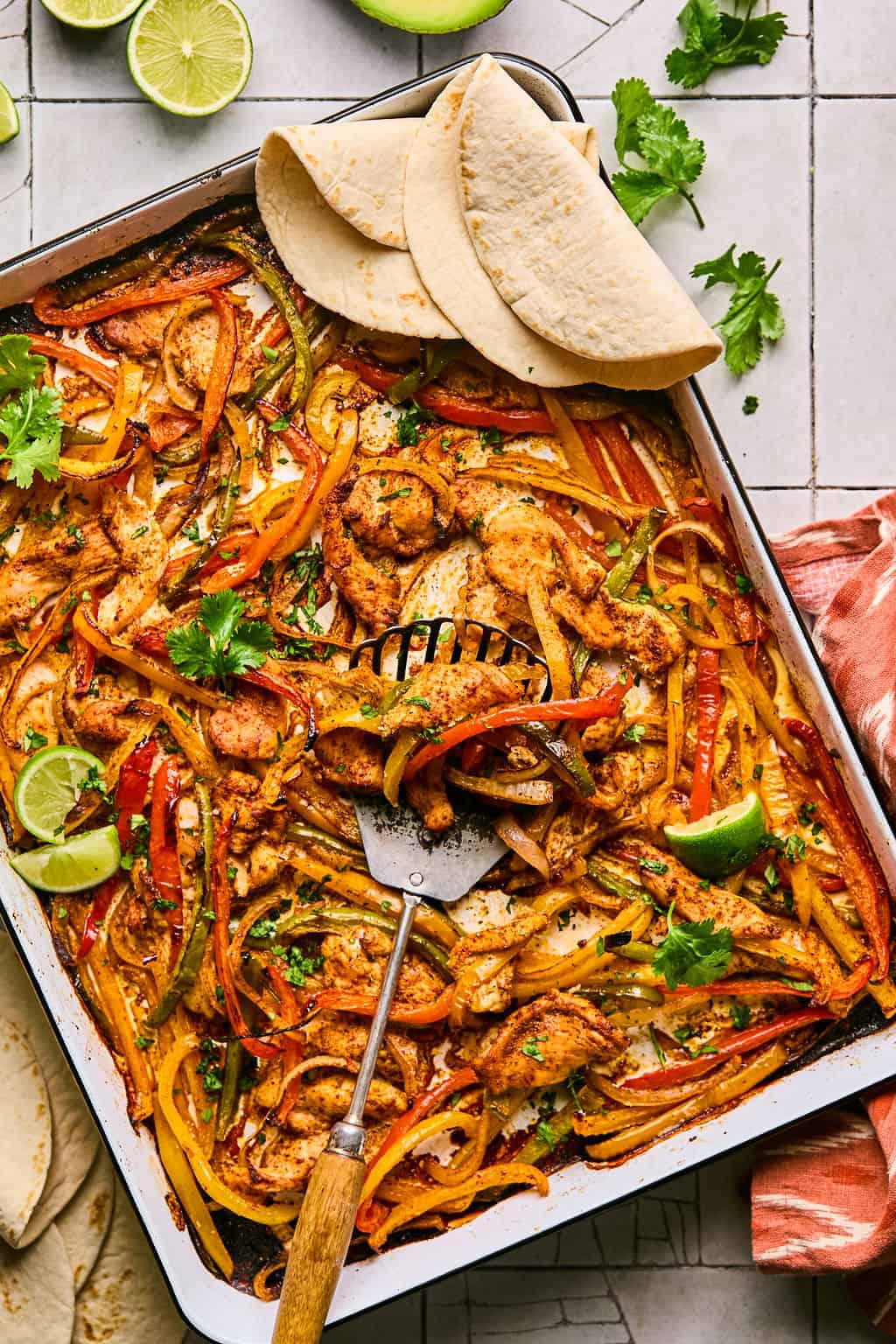 sheet pan chicken fajitas after baking on the cookie sheet with tortillas on the side.