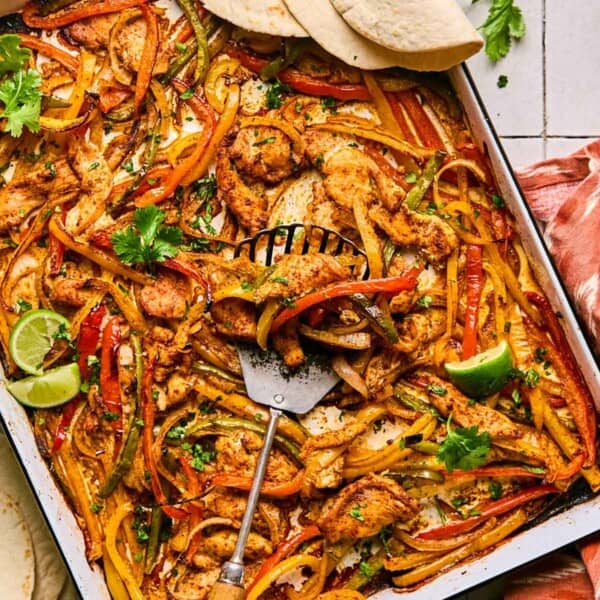 sheet pan chicken fajitas with tortillas on the side.