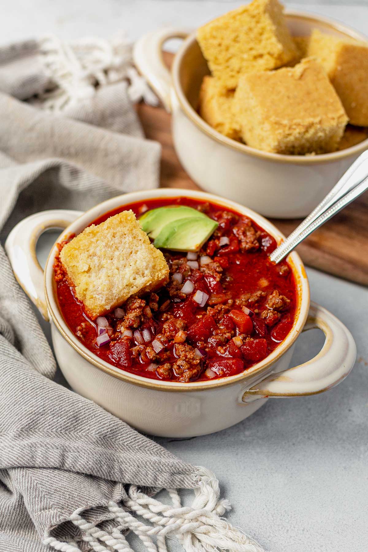 beanless chili in a white bowl with avocado and cornbread