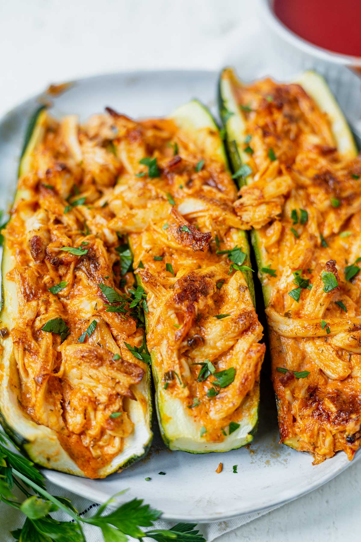 three buffalo chicken stuffed zucchini boats on a plate