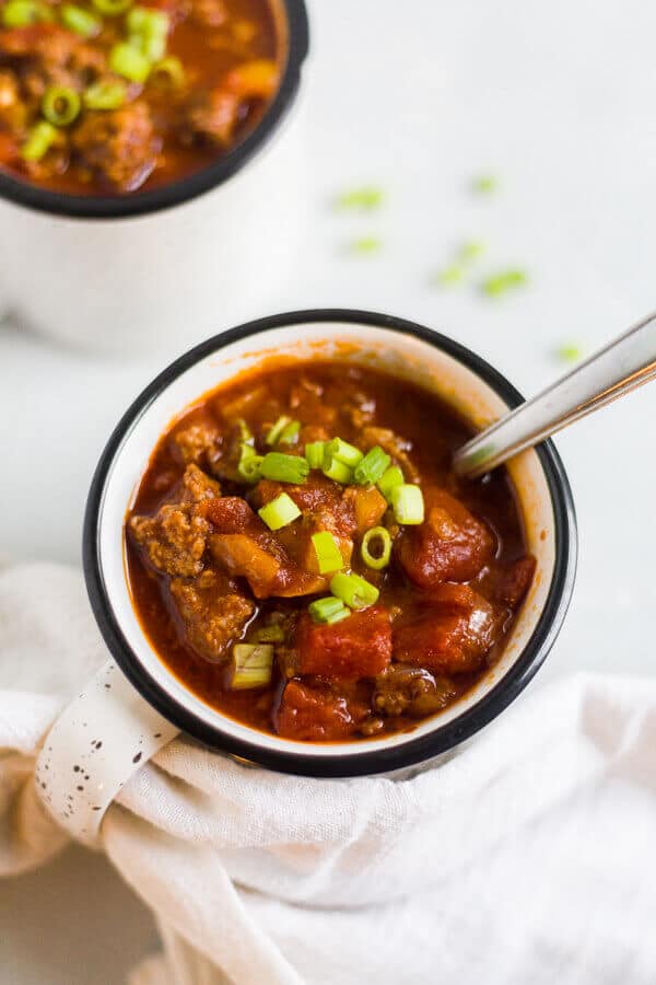paleo chili in a mug with scallions and a spoon