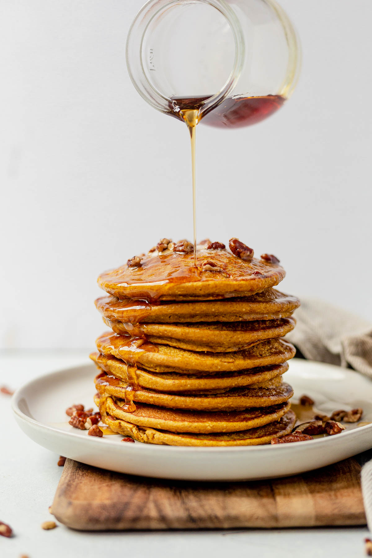 a stack of healthy pumpkin pancakes with maple syrup drizzling down the side