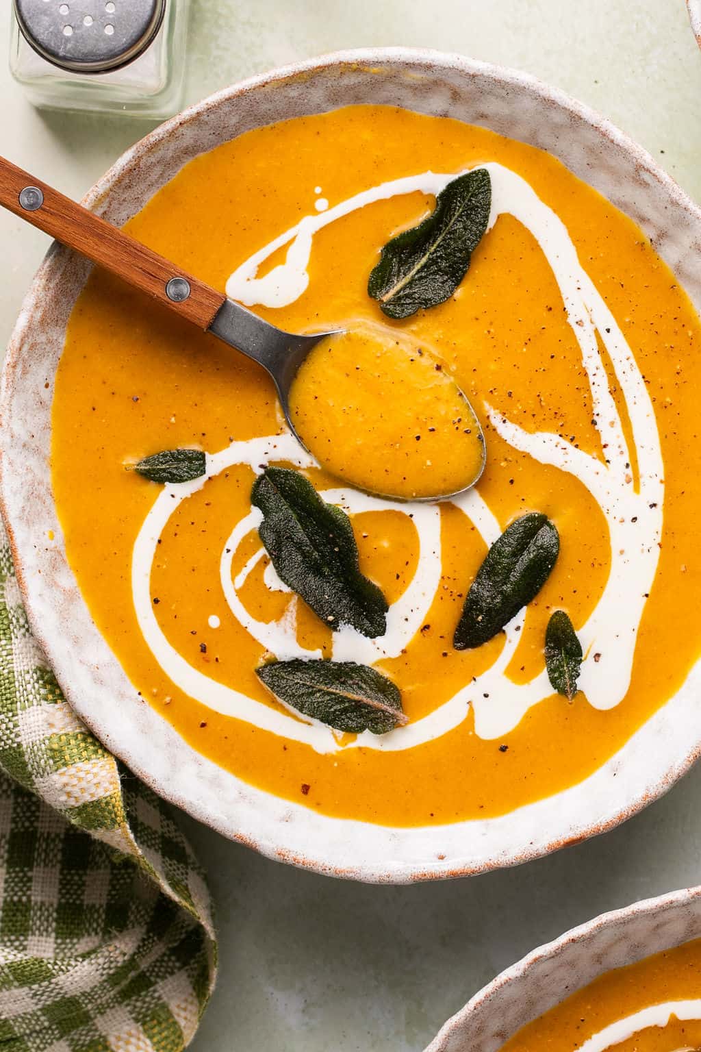 roasted butternut squash soup in a bowl with cream and crispy sage.