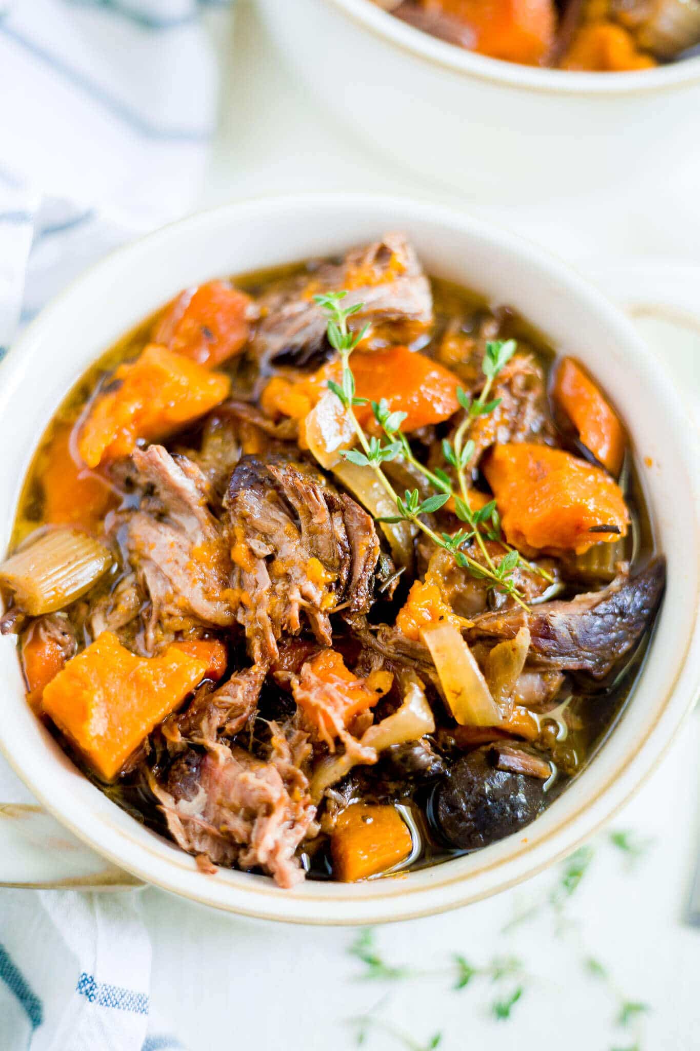 beef and sweet potato stew in a bowl with fresh thyme