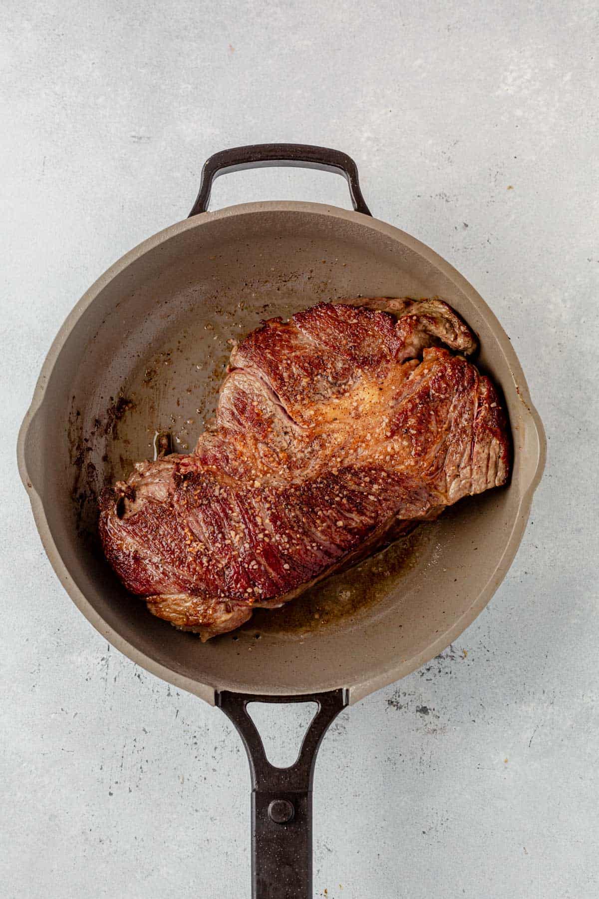 chuck roast searing in a skillet.