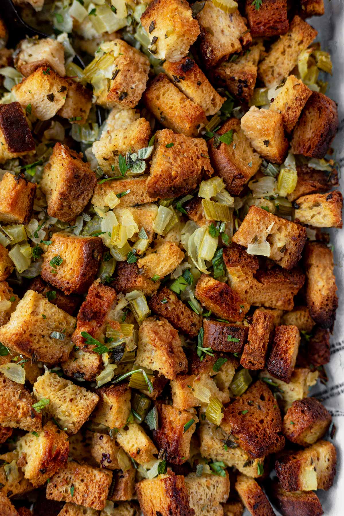 close up of gluten free stuffing baked in a dish topped with fresh herbs