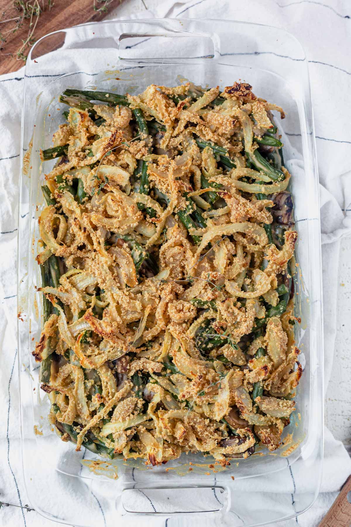 creamy dairy free green bean casserole in a glass dish topped with gluten free french onions
