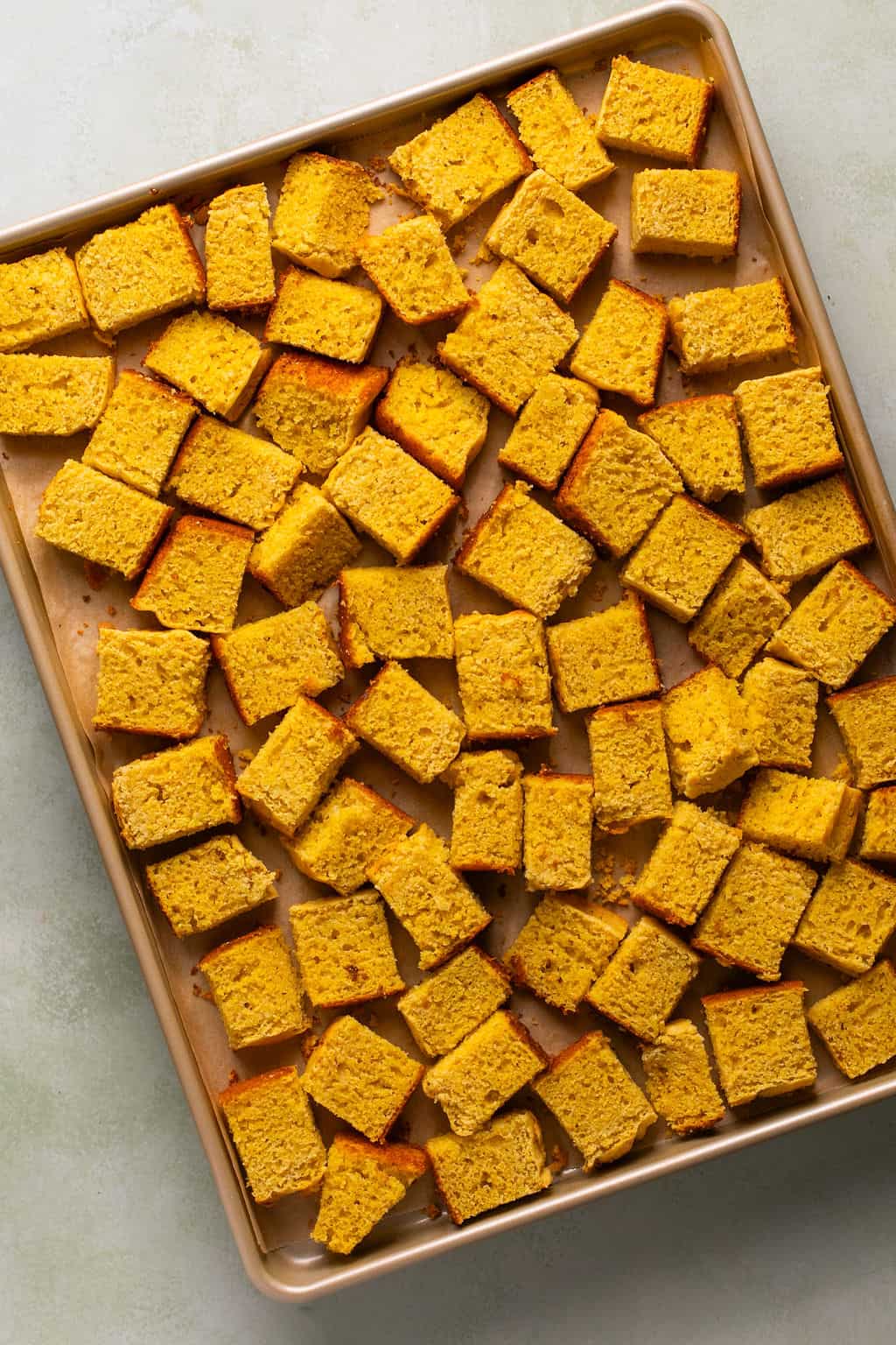 gluten free cornbread cubed and drying out on a sheet pan.