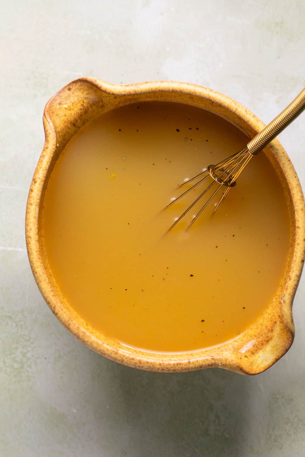 eggs and broth in a mixing bowl with a whisk.